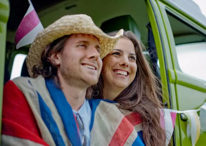 Smiling woman with boyfriend in camper van looking away