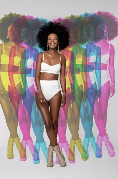 Smiling Afro woman with multiple exposure standing against white background