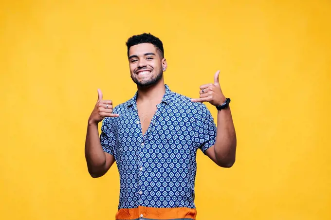 Smiling handsome man gesturing against yellow background