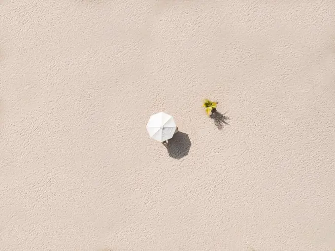 Aerial view of single beach umbrella on sandy beach