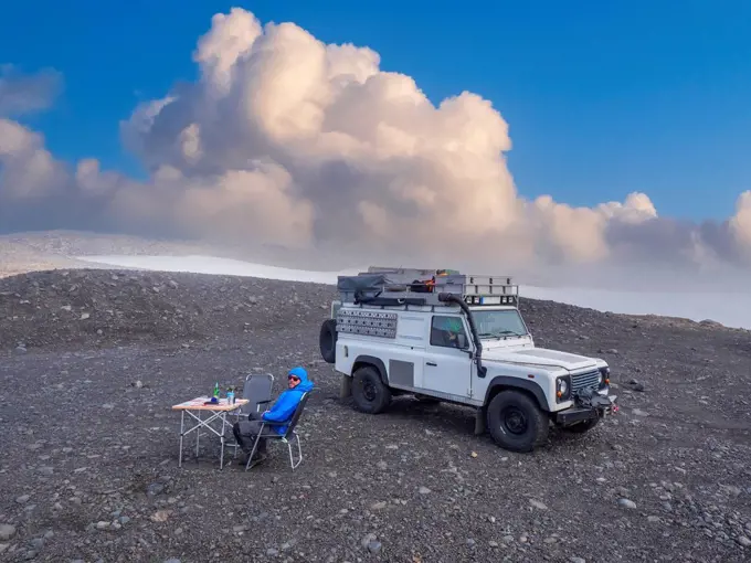 Man camping in front of off-road vehicle at coast of Myrdalsjokull icecap