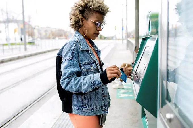 Woman using kiosk at tram station