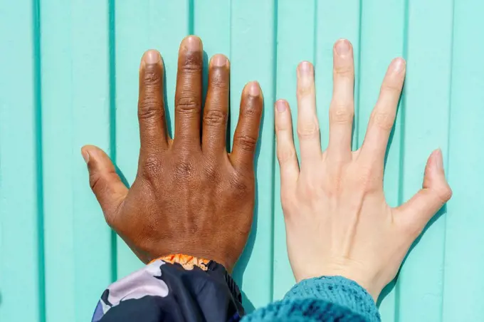 Hands of multi-ethnic male and female friends on turquoise wall