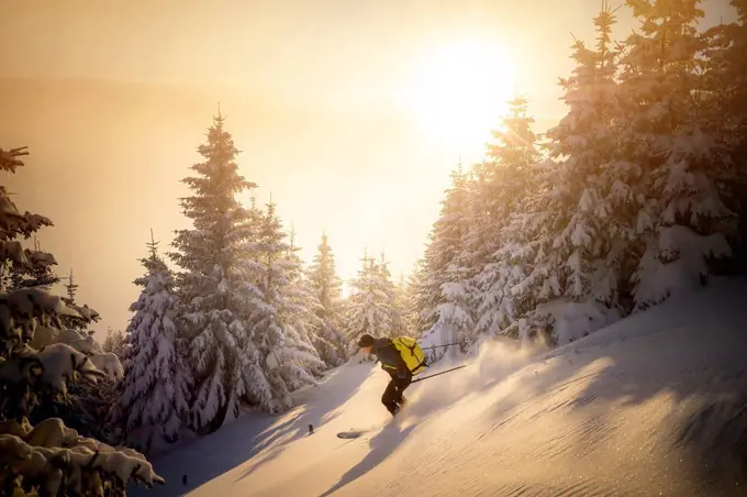 Mid adult man skiing on snowy mountain during sunrise