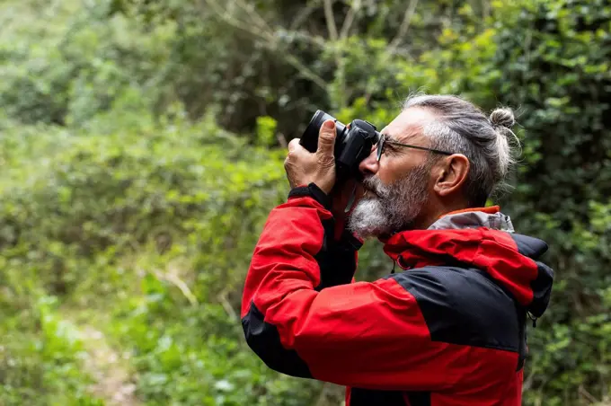 Male explorer photographing in forest