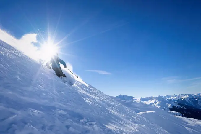 Sun shining over man skiing in¶ÿArlberg¶ÿmassif