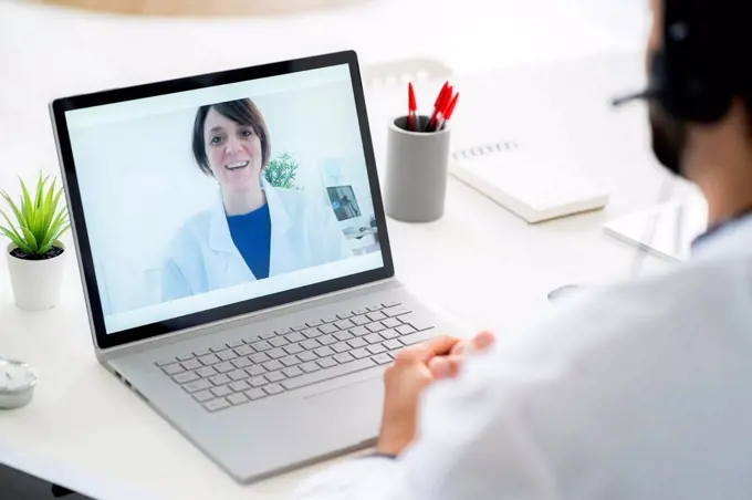 Male doctor discussing with female colleague on video conference through laptop