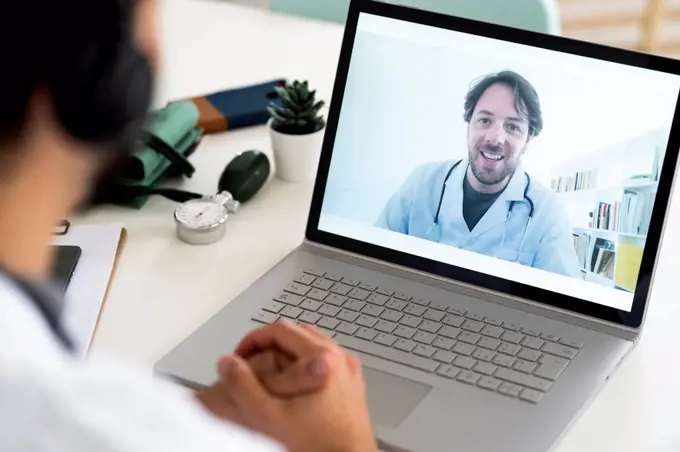 Male healthcare worker discussing with doctor through video conference
