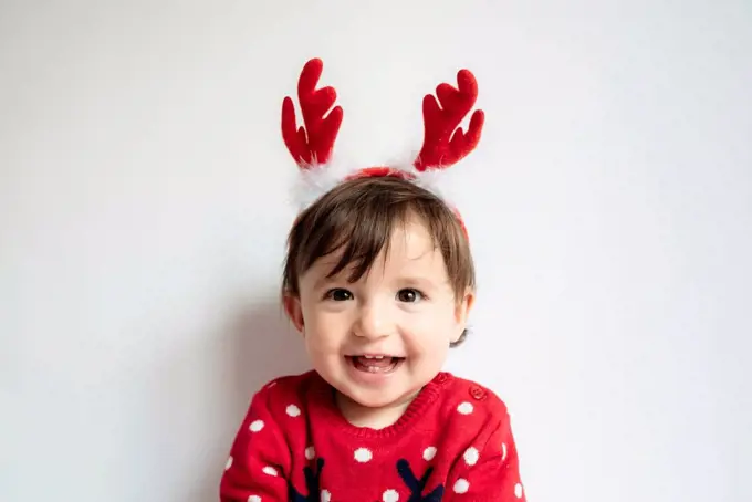Portrait of laughing baby girl wearing reindeer antlers headband