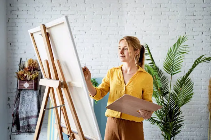 Woman in casual clothing painting at home