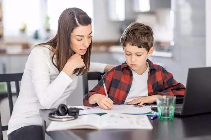 Woman assisting son studying at home