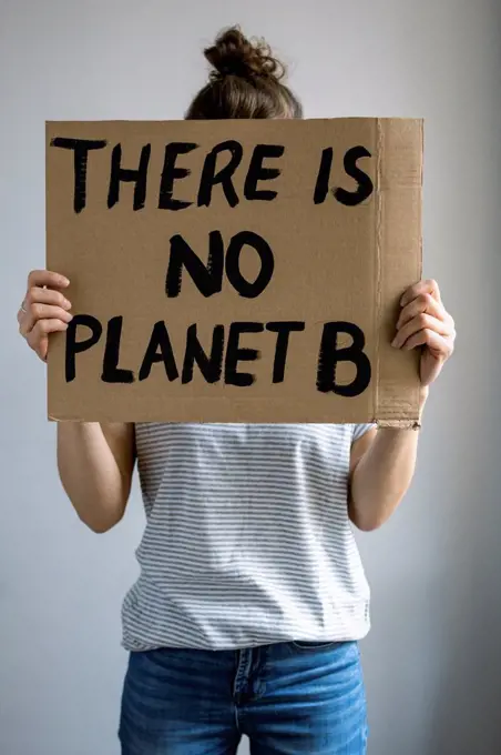 Woman holding environment protection message cardboard in front of studio