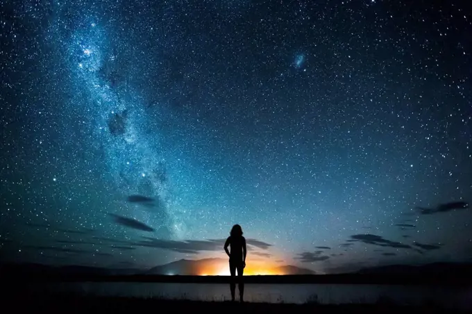 New Zealand, Canterbury, Twizel, Silhouette of man looking at Lake Poaka under starry sky