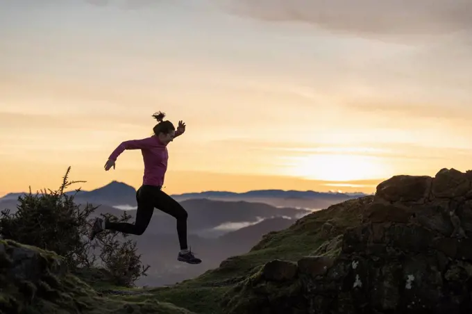 Young woman jumping while running during sunrise