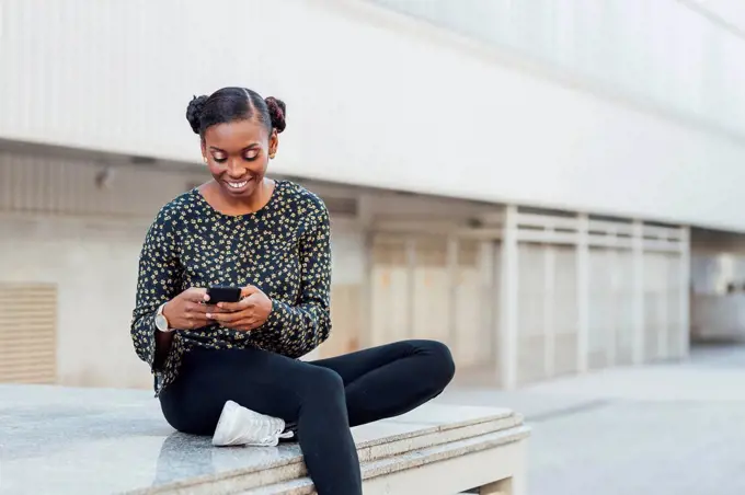 Mid adult woman smiling while using mobile phone