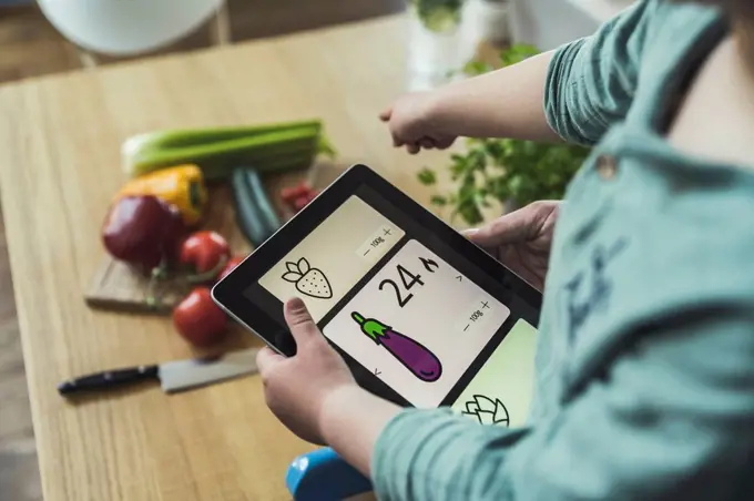 Boy holding digital tablet pointing at vegetables