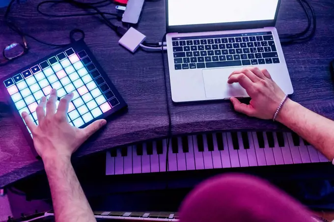 Man using digital tablet and laptop while composing music at studio