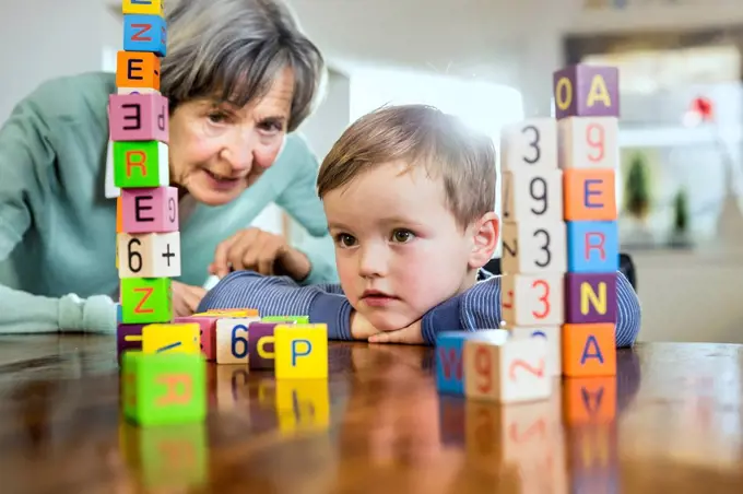 Senior woman and boy looking at toy block stack on table