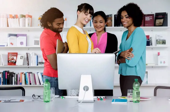 Smiling male and female entrepreneurs working in front of computer at office
