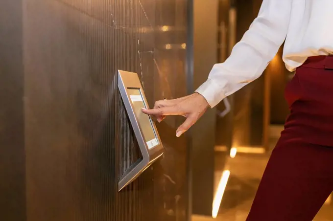 Female professional touching device screen at elevator
