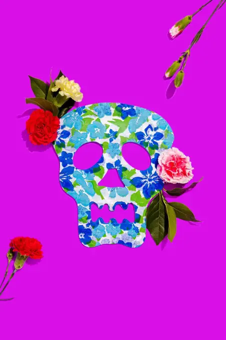 Studio shot of blooming roses and blue skull mask decorated with floral pattern