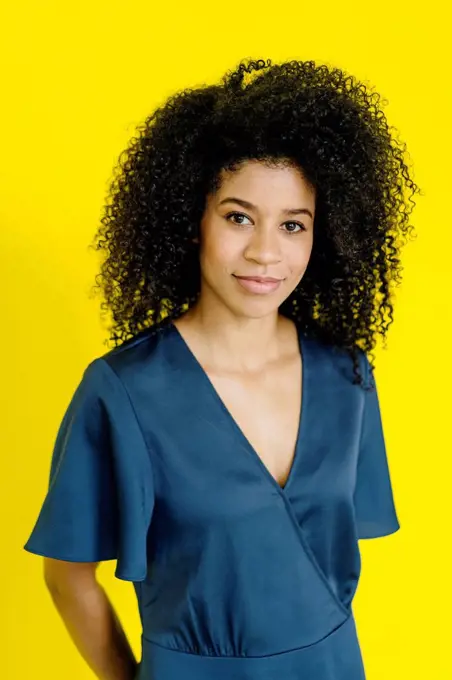 Businesswoman with frizzy hair standing at yellow background