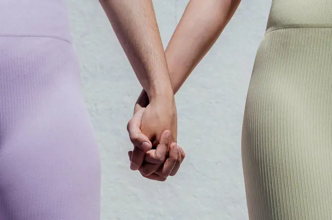Sportswomen holding hands while standing in front of wall