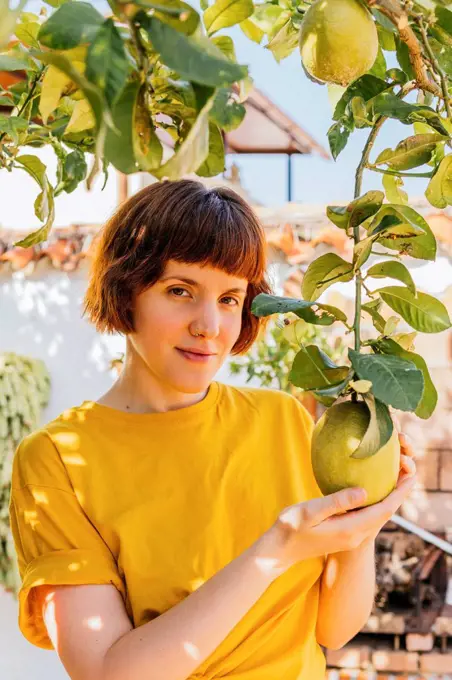 Beautiful woman touching lemon fruit in home garden