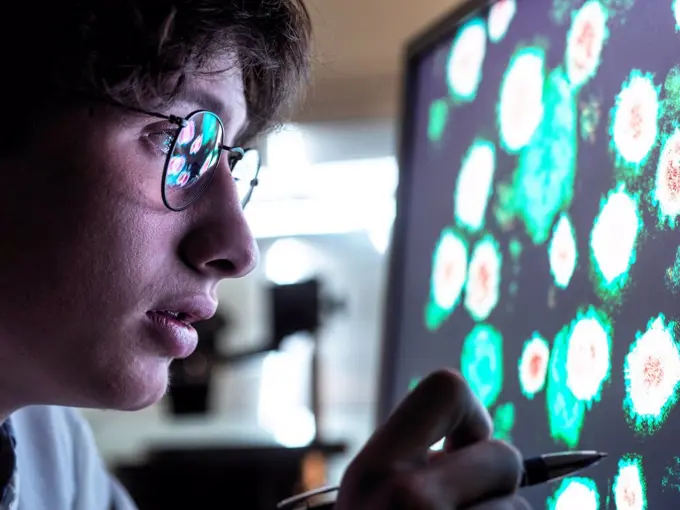 Male scientist researching on biological cell on computer screen in laboratory