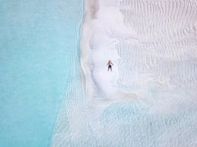 Aerial view of lone man sunbathing on sandy coastal beach of¶ÿThulusdhoo island