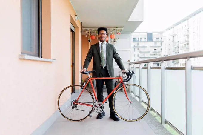 Businessman standing with bicycle at balcony