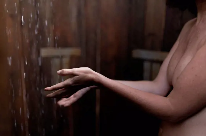 Shirtless woman taking shower in cabana