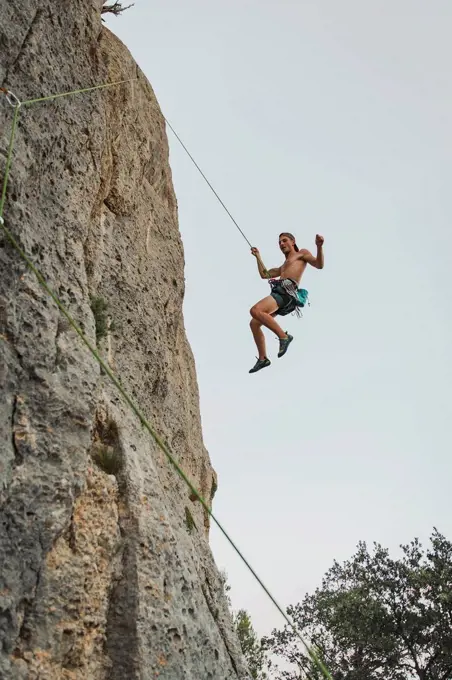 Male climber hanging through rope on rock mountain