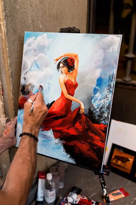 Creative male street artist painting female on canvas