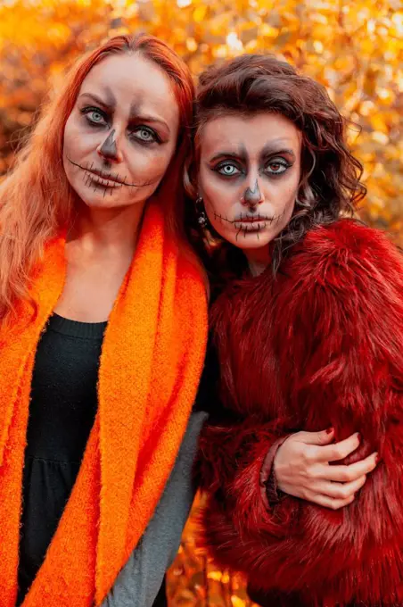 Female friends with Halloween make-up and costume standing in forest