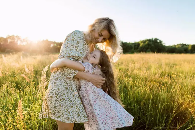 Smiling mother embracing daughter at meadow