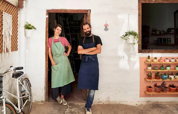Male and female entrepreneurs wearing apron at doorway