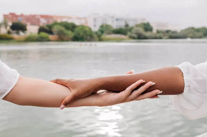 Female friends holding hands by lake