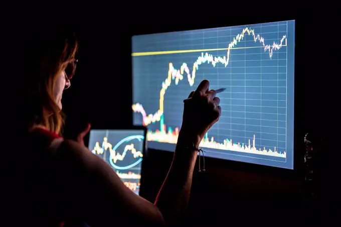Businesswoman checking stock market data on screen in office