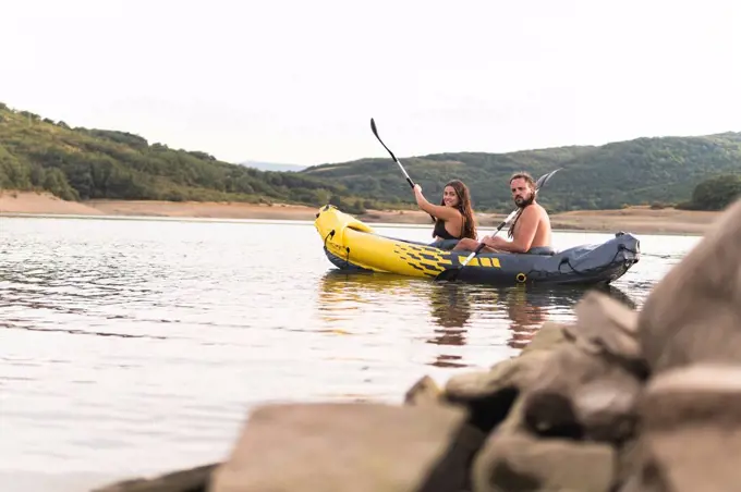 Male and female friends rowing in lake during vacation