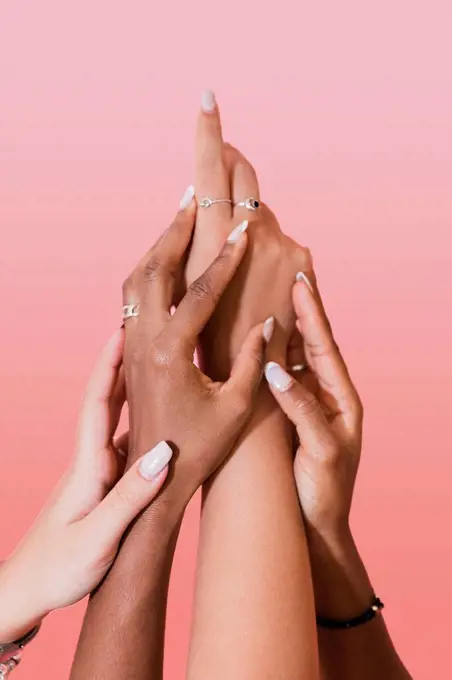 Multiracial lesbian women touching hands against pink background