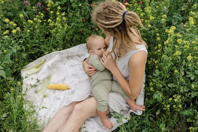 Woman breastfeeding toddler girl amidst flowering plants