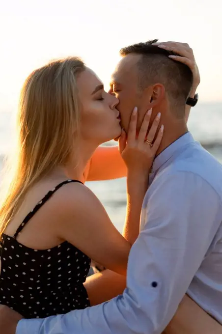 Blond woman kissing man at sunset