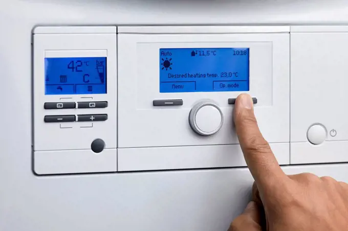 Man operating control panel of heating boiler at home