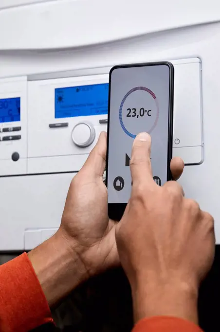 Man adjusting boiler temperature through mobile phone at home