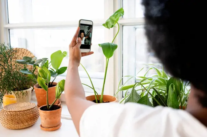 Vlogger filming on smart phone by plants at home