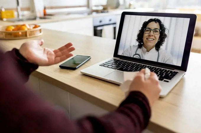 Woman doing video call with doctor on laptop at home