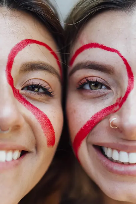 Smiling women with red heart shape on face