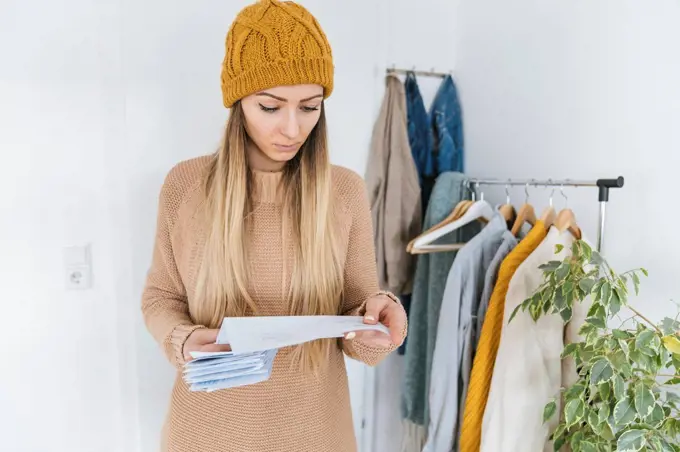 Woman with wooly checking bills standing in dressing room