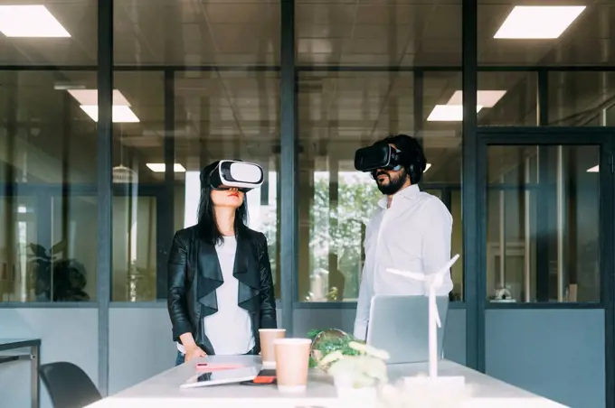 Business colleagues wearing VR glasses at work place